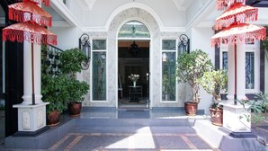 A grand entrance with a central archway, potted plants, and red umbrellas.