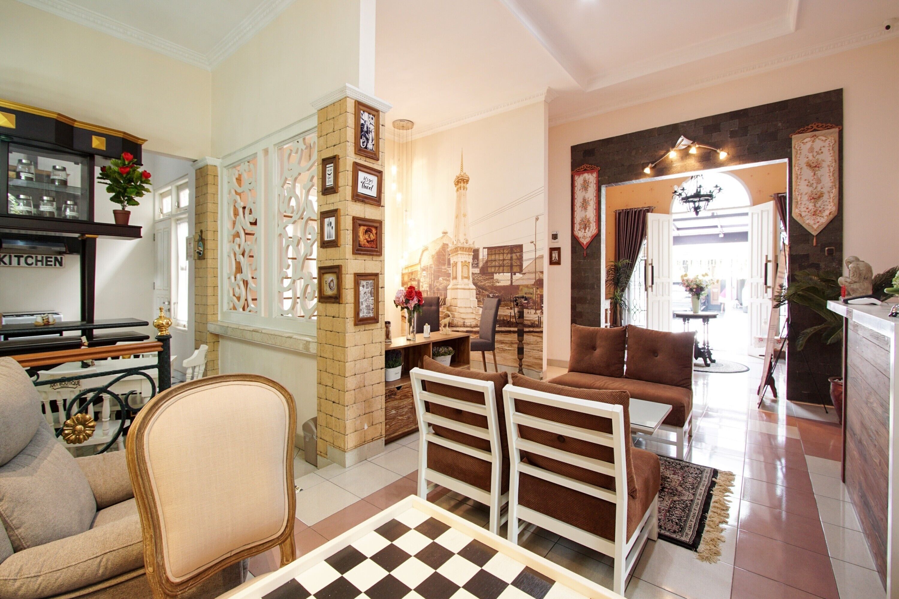 A spacious living room with a checkered floor, a sofa, a dining table, and a kitchen area with a sign that reads "KITCHEN".
