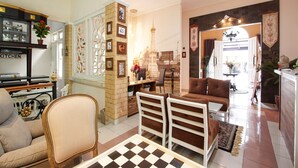 A spacious living room with a checkered floor, a sofa, a dining table, and a kitchen area with a sign that reads "KITCHEN".