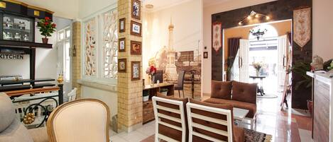 A spacious living room with a checkered floor, a sofa, a dining table, and a kitchen area with a sign that reads "KITCHEN".