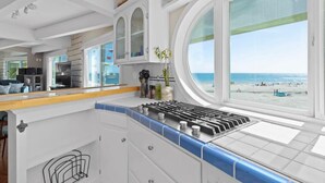 A kitchen with a view of the beach, white cabinetry, and a stove. - Rio Del Mar Boathouse - steps from the beach (Aptos)