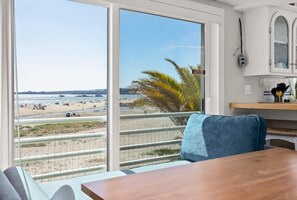 A room with a large sliding glass door leading to a beach view. - Rio Del Mar Boathouse - steps from the beach (Aptos)