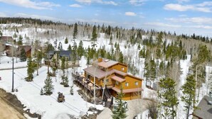 Un amplio lodge de madera con varios niveles y una escalera destacada, rodeado por un bosque nevado.