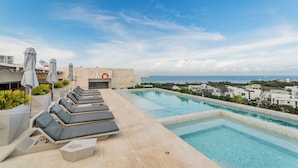 A rooftop pool area with lounge chairs, umbrellas, and a lifebuoy. - Nuevo Departamento con Playa Privada en Puerto Cancún (Cancún)