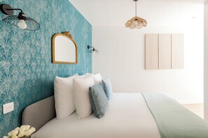 A bedroom with a bed, pillows, a mirror, wall sconces, and a hanging light fixture. - Family Suite - Tour Eiffel - Finlay (Paris)