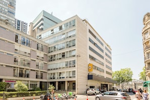 A multi-story hotel with a modern facade, large windows, and a prominent yellow sign. - Family Suite - Tour Eiffel - Finlay (Paris)