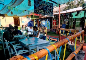 An outdoor dining area with tables and chairs, a wooden fence, and a mural on the wall. - valle verde (Urubamba)