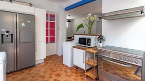 A compact kitchen with a refrigerator, microwave, oven, and a water dispenser.