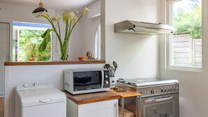 A compact kitchen with a microwave, oven, and washing machine.