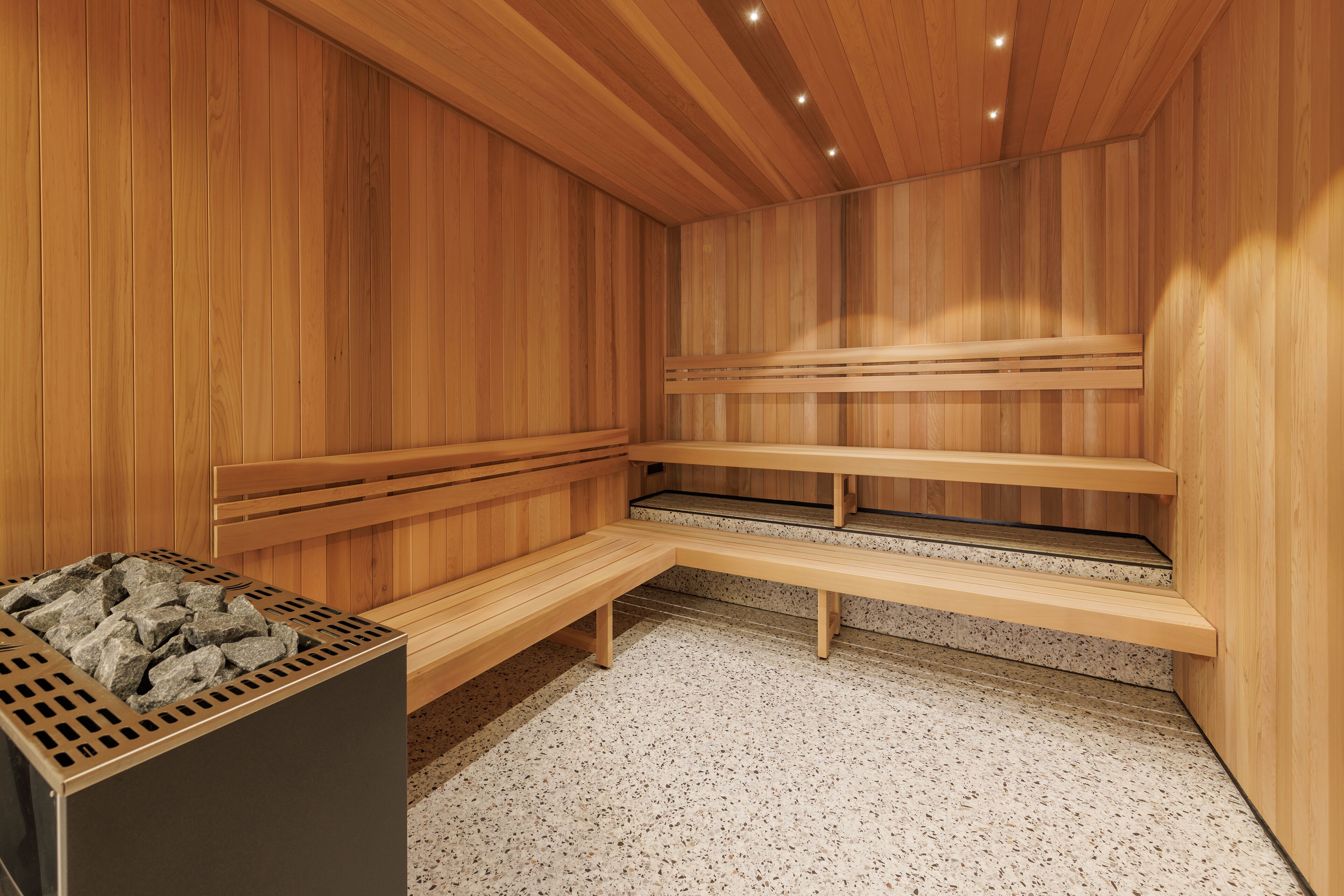 A sauna with wooden benches and a stone heating element.
