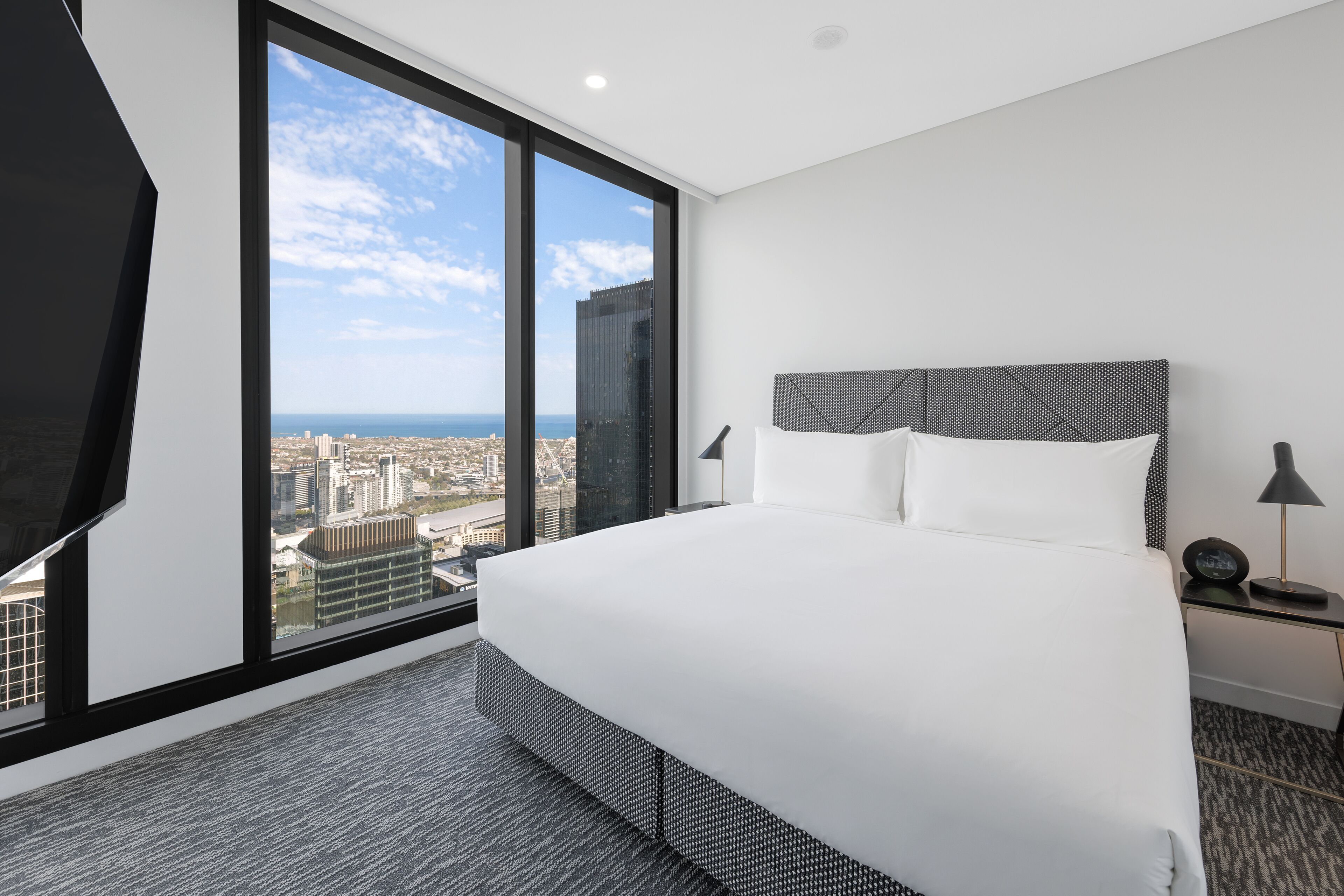 Un hotel moderno con una cama grande, vistas a la ciudad y un paisaje urbano a través de la ventana.