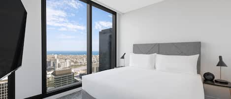 Un hotel moderno con una cama grande, vistas a la ciudad y un paisaje urbano a través de la ventana.