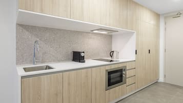 Una cocina moderna con armarios de madera, un lavamanos de acero inoxidable, una cafetera y un horno.
