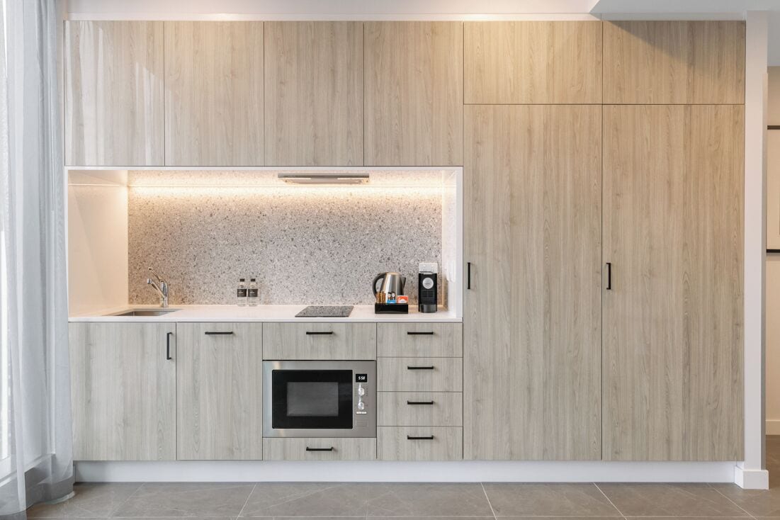 A modern kitchen with a built-in microwave, a coffee maker, and a kettle on the countertop.