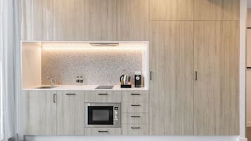 A modern kitchen with a built-in microwave, a coffee maker, and a kettle on the countertop.
