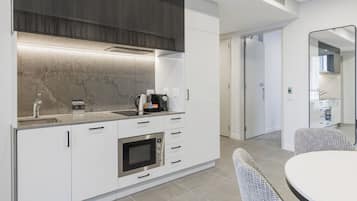 A modern kitchen with white cabinetry, a built-in oven, and a stainless steel sink.