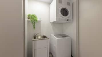 Un lavadero pequeño con lavadora, lavabo y un mueble.