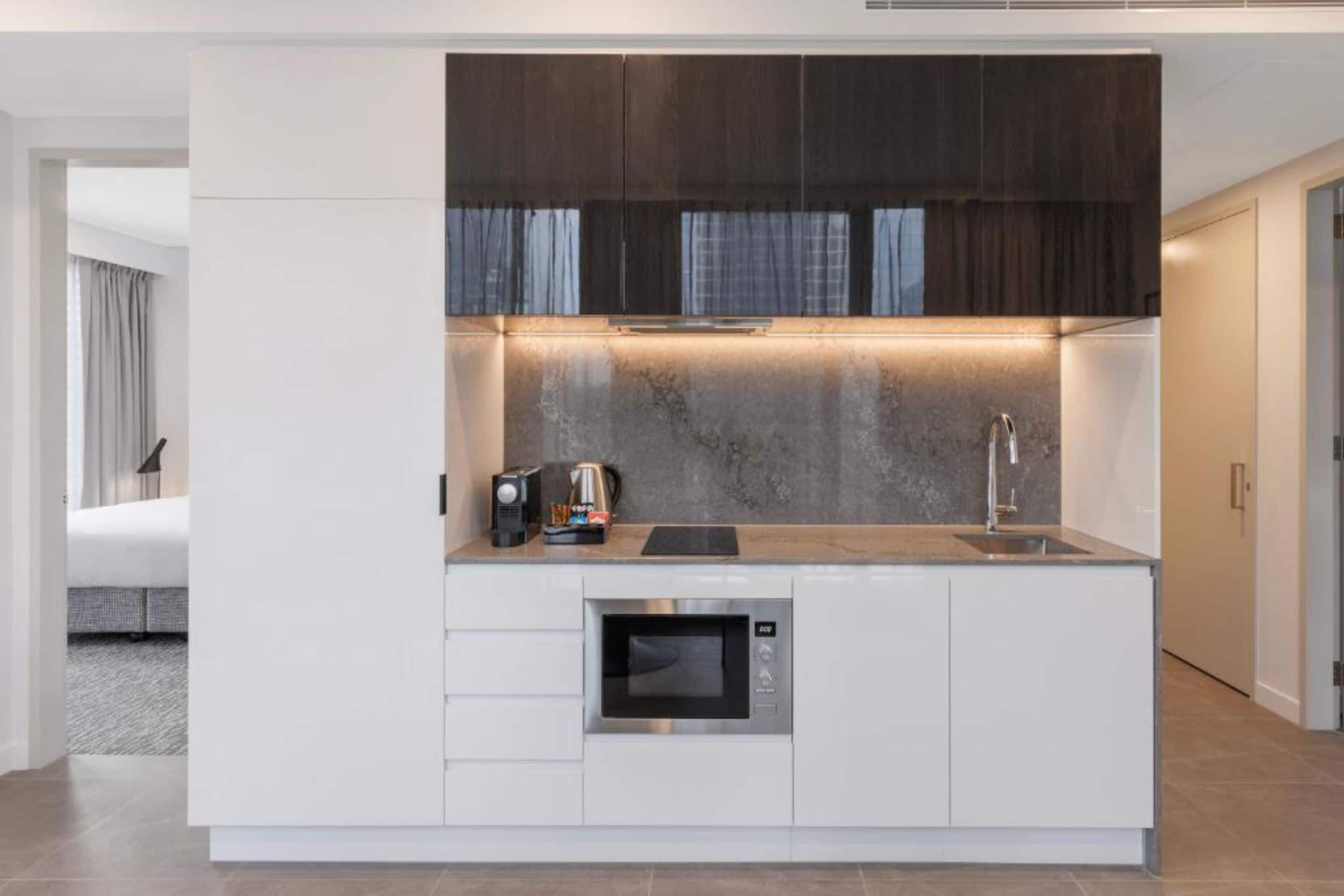 A modern kitchen with a built-in oven, a coffee maker, and a sink.
