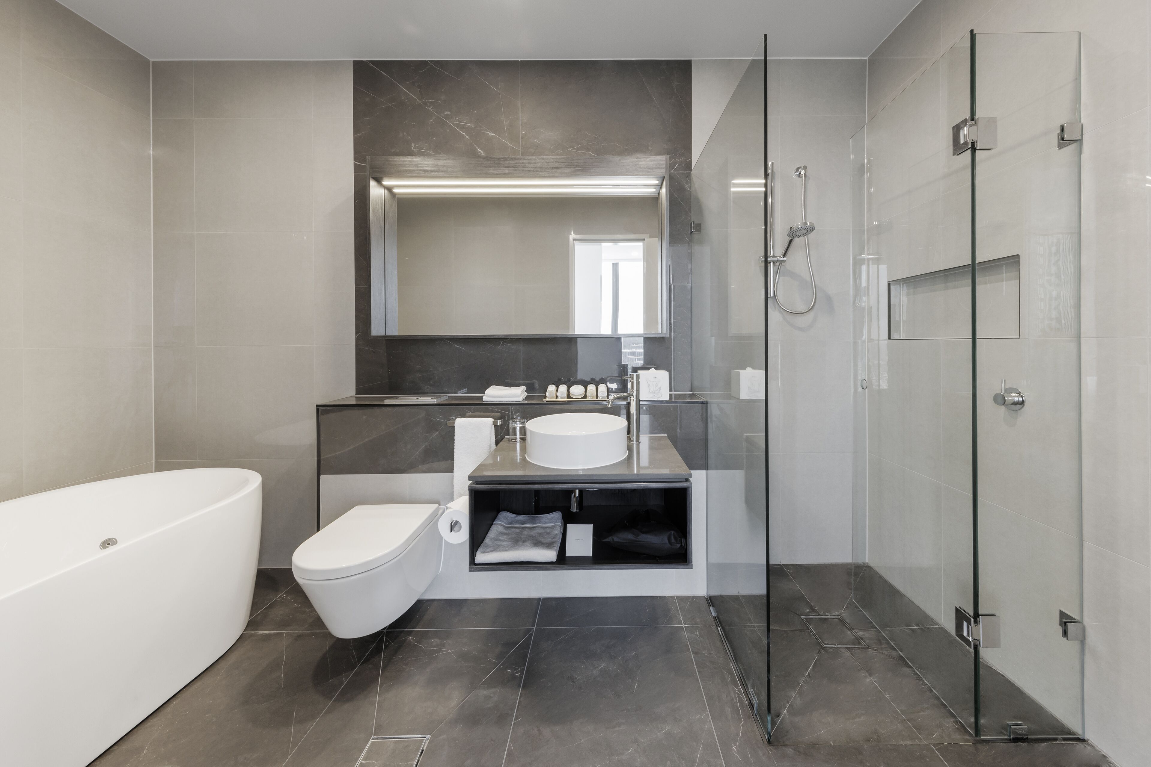 A modern bathroom with a freestanding bathtub, a glass-enclosed shower, and a vanity with a mirror above the sink.