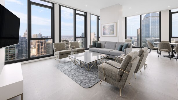 A modern living room with a large window, a sofa, a coffee table, and a TV.