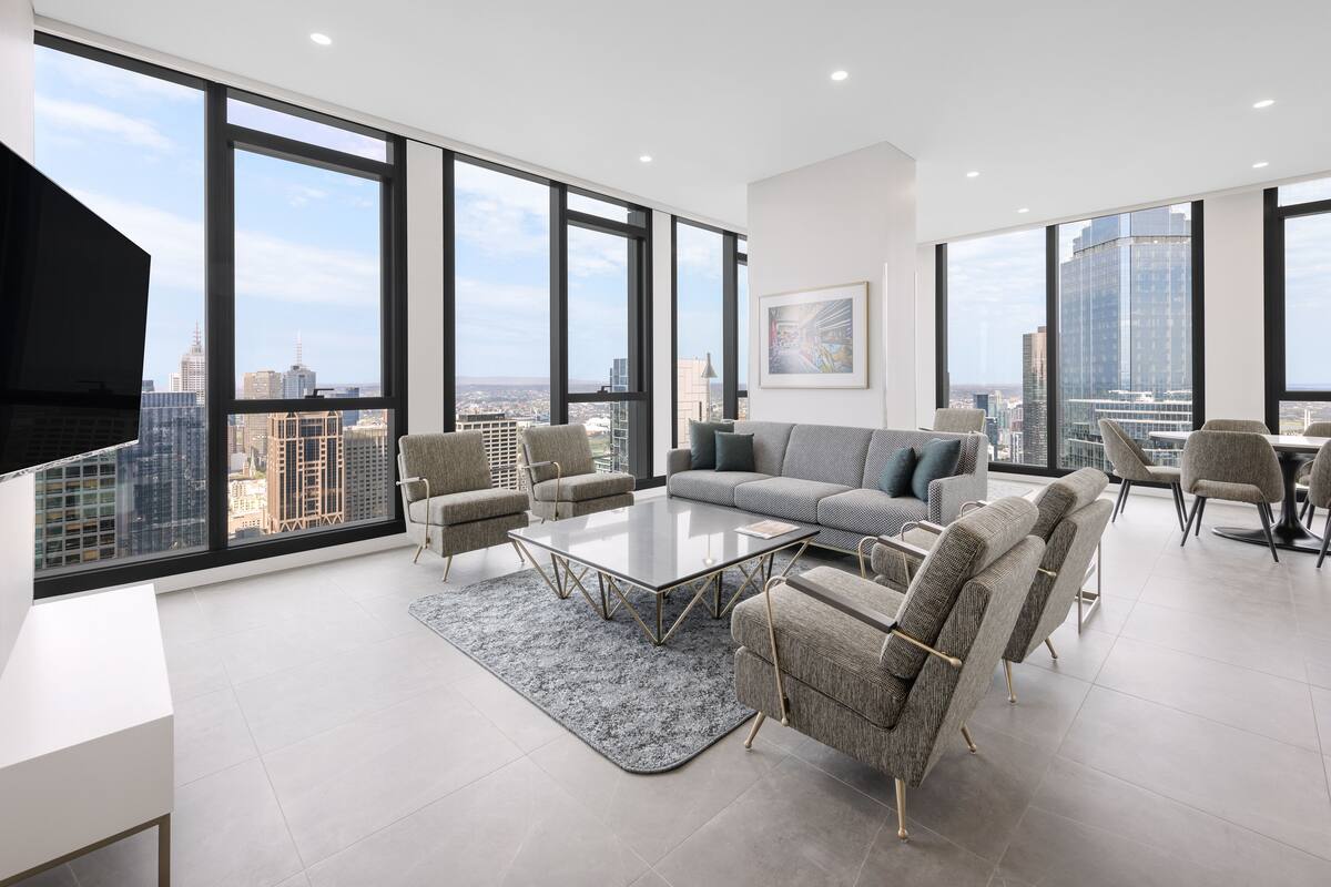A modern living room with a large window, a sofa, a coffee table, and a TV.