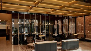 A modern lobby with a reception desk, seating area, and large windows.