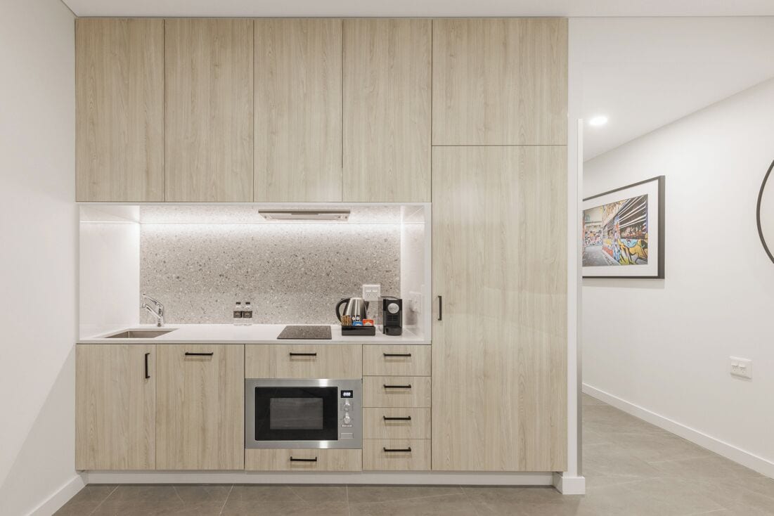 A modern kitchen with built-in appliances, a countertop, and a wall-mounted artwork.