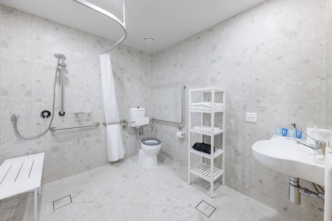 A bathroom with a toilet, shower, and sink.