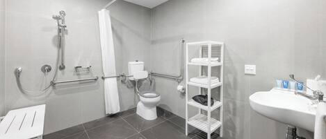 A modern bathroom with a shower, toilet, and sink.