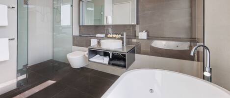 A modern bathroom with a glass-enclosed shower, a freestanding bathtub, a vanity with a sink, and a large mirror.