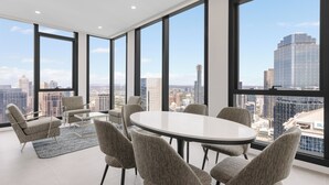 A modern conference room with a round table and six chairs, large windows offering a city view.