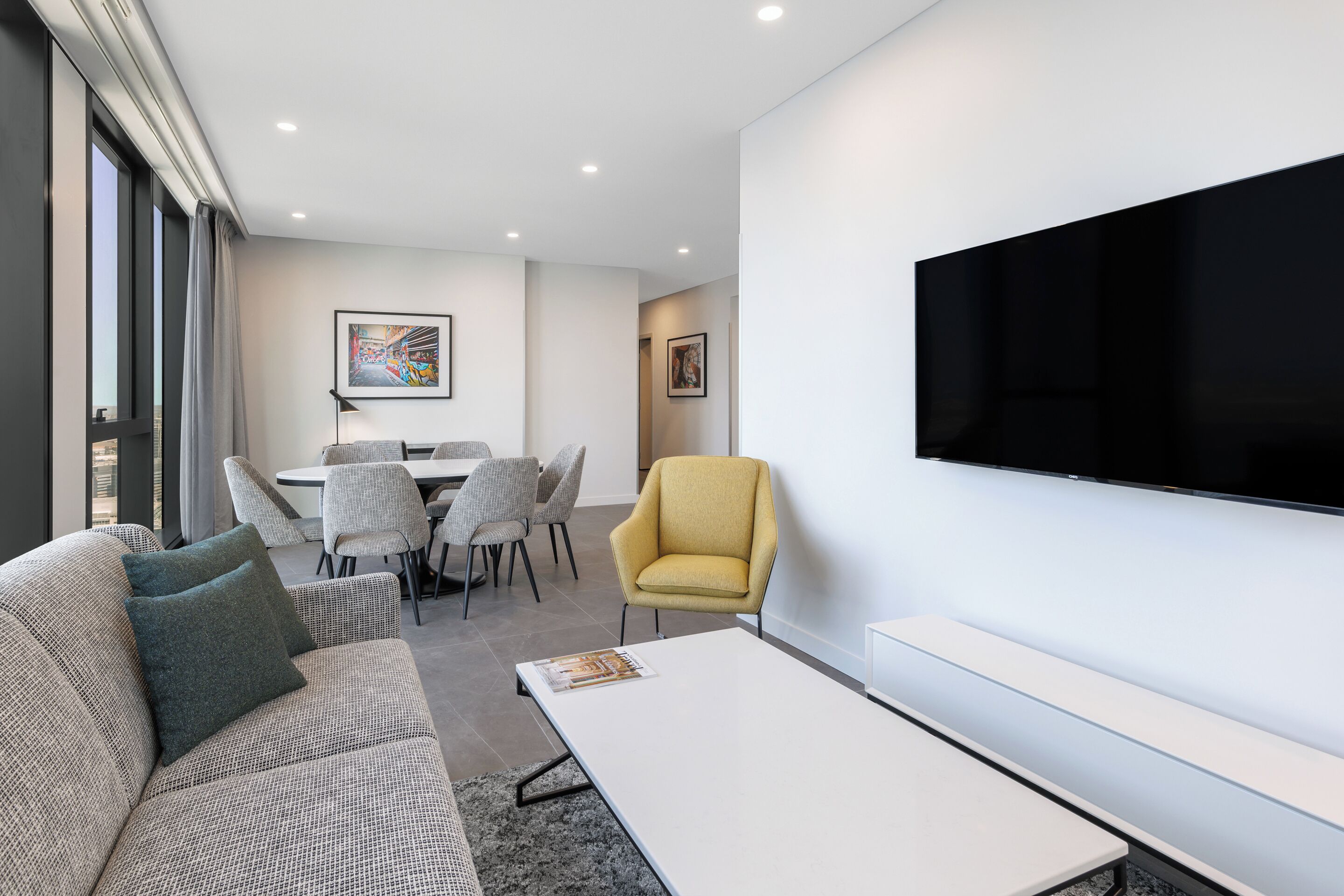 Una sala de estar moderna con un sofá, un sillón y un televisor de pantalla plana montado en la pared.