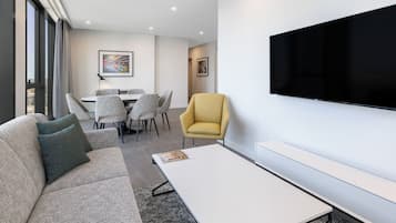 Una sala de estar moderna con un sofá, un sillón y un televisor de pantalla plana montado en la pared.