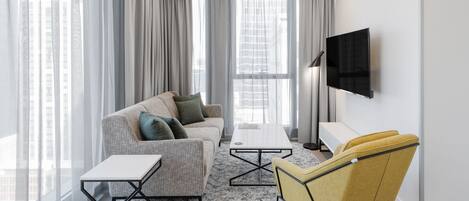 A modern living room with a sofa, a yellow armchair, a coffee table, and a TV mounted on the wall.