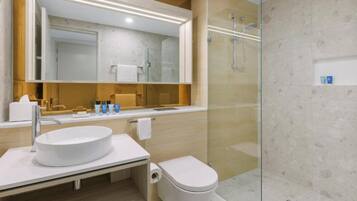 Un bany modern amb un lavabo rodó, un vàter i una zona de dutxa amb envàs de vidre.