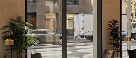 Un interior moderno con ventanas amplias, una zona de estar con dos sillones, una mesita y una planta en maceta.
