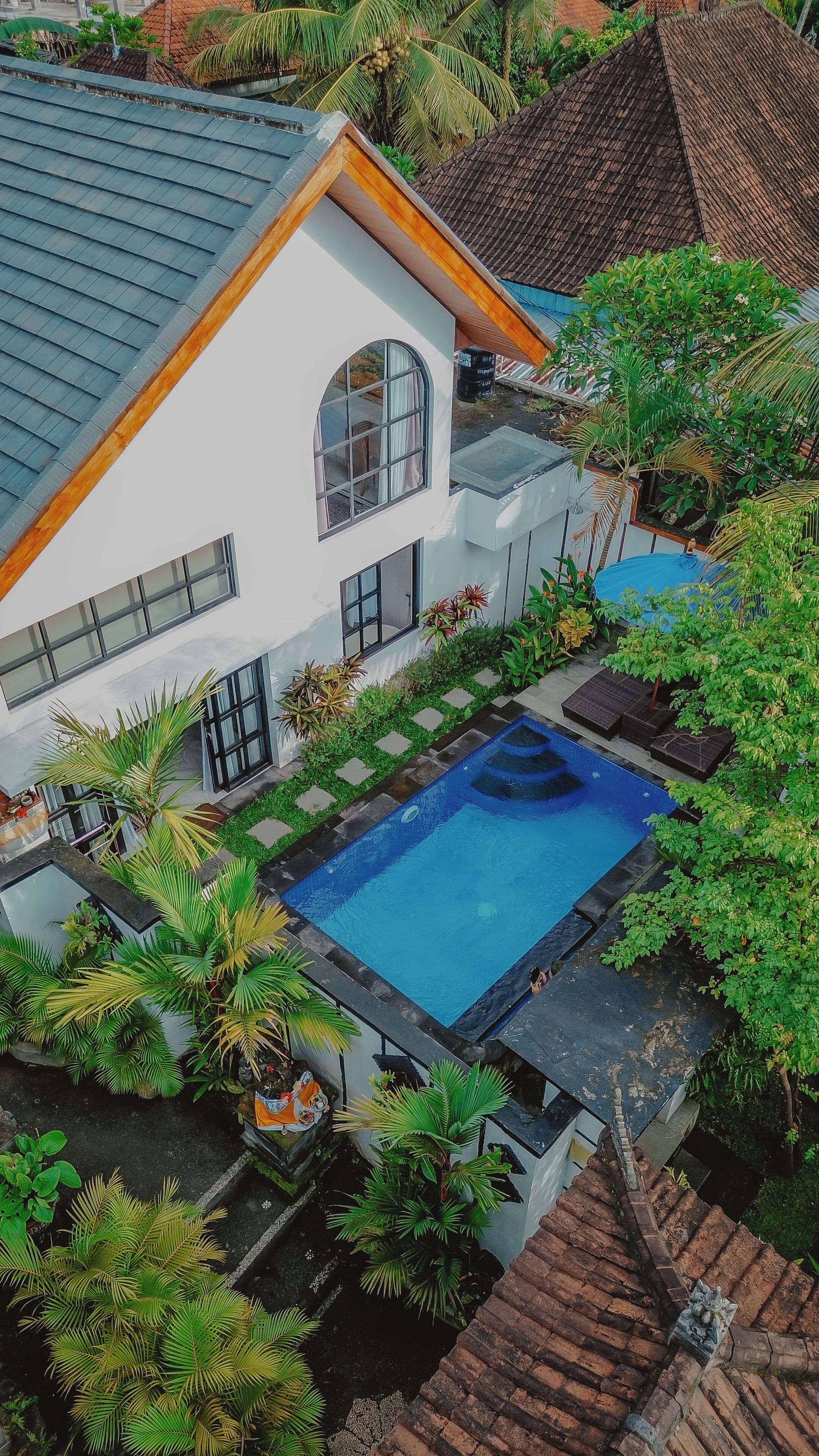 Una casa moderna con piscina, rodeada de exuberante vegetación y un jardín bien cuidado.