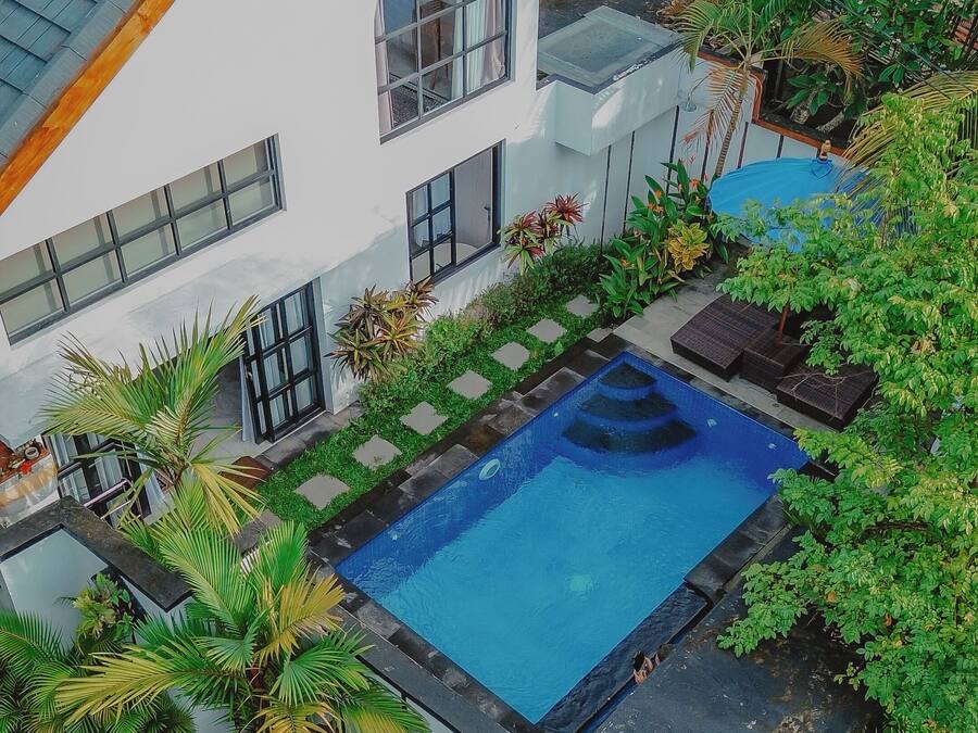 A modern house with a swimming pool, surrounded by lush greenery and a well-maintained garden.