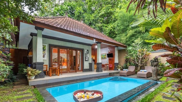 Una casa con piscina, un arreglo de comida con forma de corazón junto a la piscina, y un jardín exuberante.