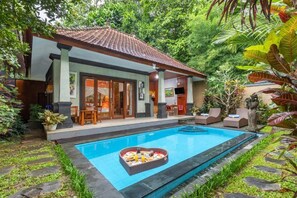 Una casa con piscina, un arreglo de comida con forma de corazón junto a la piscina, y un jardín exuberante.