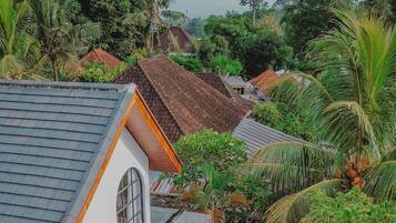 A residential area with a swimming pool surrounded by lush greenery and a white building with a tiled roof.