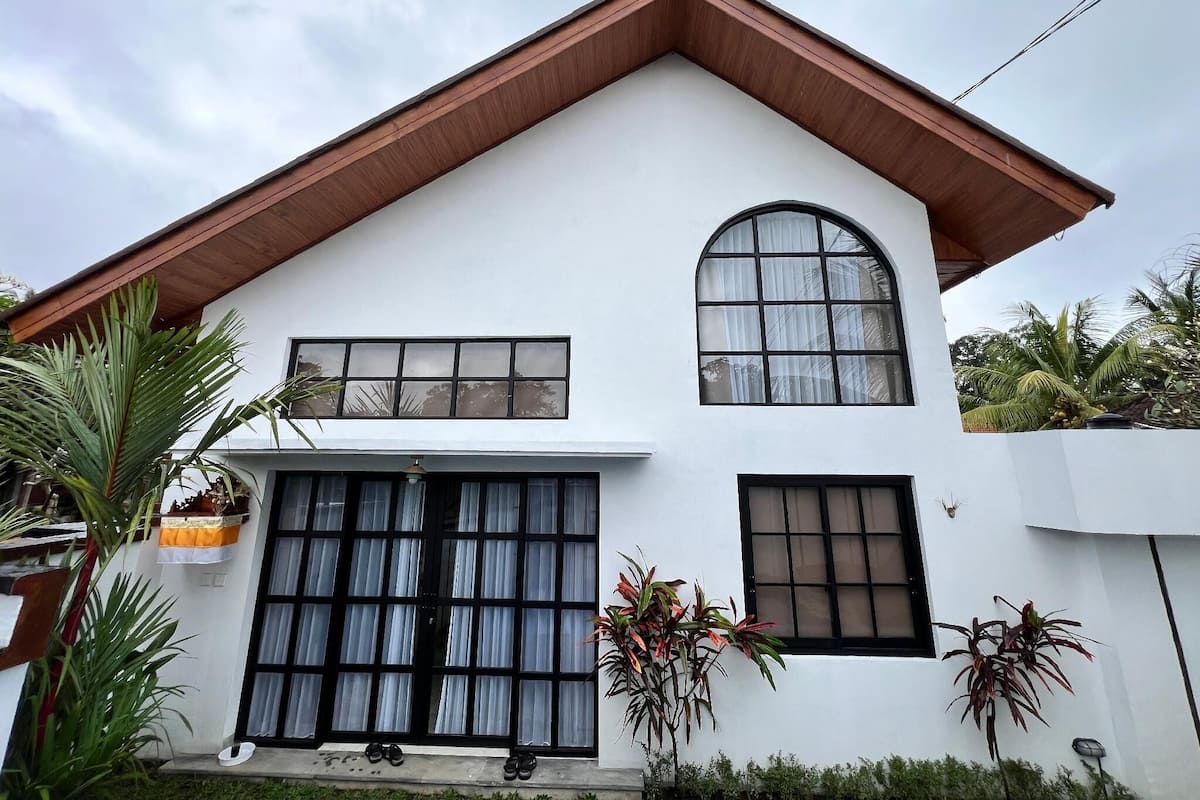 A modern two-story house with a white facade, a pitched roof, and large windows.