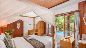 Un dormitorio con cama a dosel, muebles de madera, una mesita y vistas a una piscina.