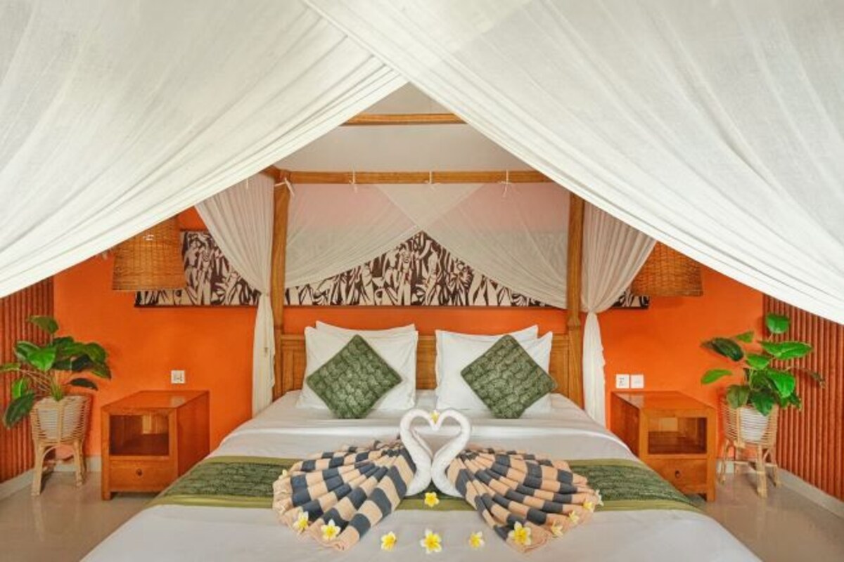 A bedroom with a bed, two nightstands, a canopy, and a wall with a patterned design.