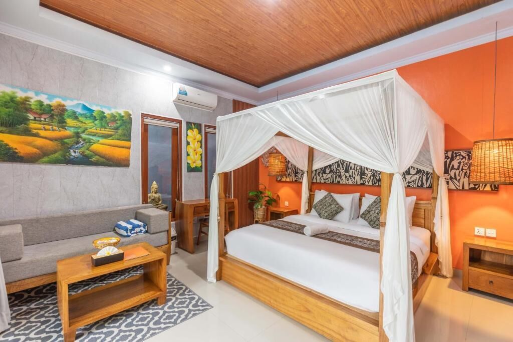 A room with a bed under a canopy, a sofa, a coffee table, and a painting on the wall.