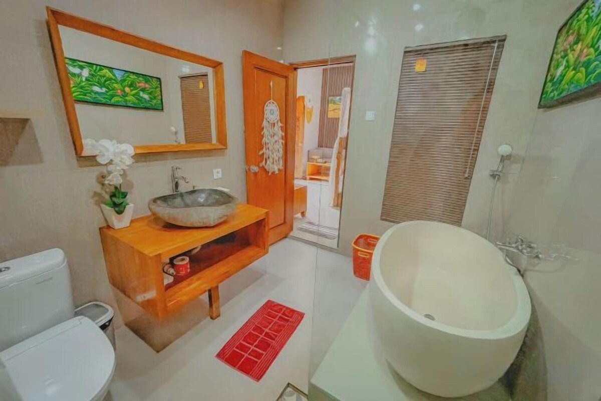 A bathroom with a wooden vanity, a large bathtub, and a toilet.