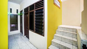 Un pasillo con suelo de baldosas, una puerta de madera y una ventana con persianas.