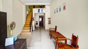 Una sala de estar con una escalera de madera, una mesa de comedor con sillas, un televisor y un calendario sobre un escritorio.