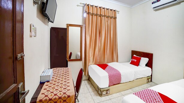 Habitación de hotel con cama, escritorio, silla, televisor, aire acondicionado y espejo.