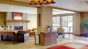 A spacious lobby with a stone fireplace, a wooden reception desk, and a large window offering a view of the outdoors.